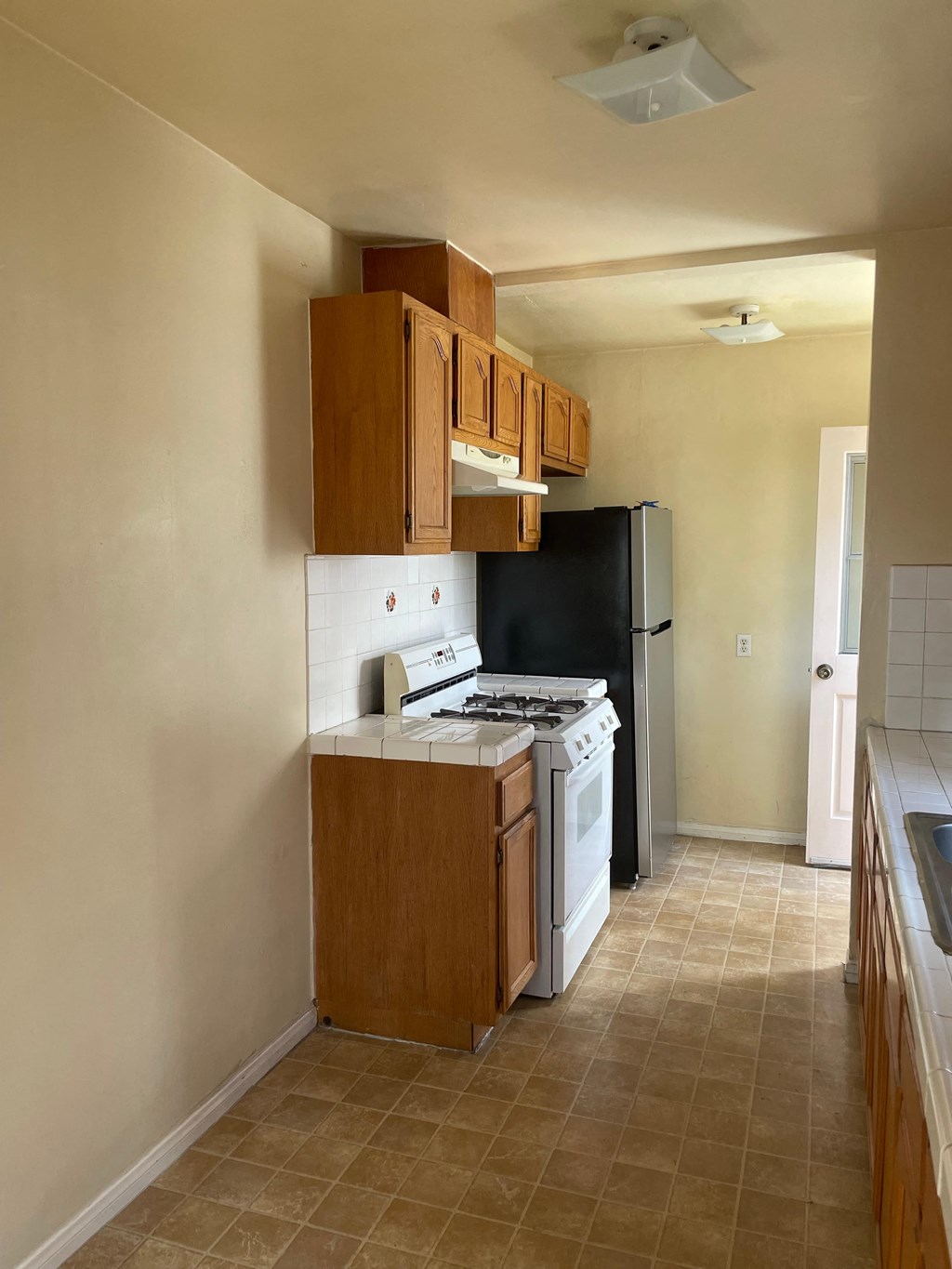 a kitchen with a stove and refrigerator and wooden cabinets