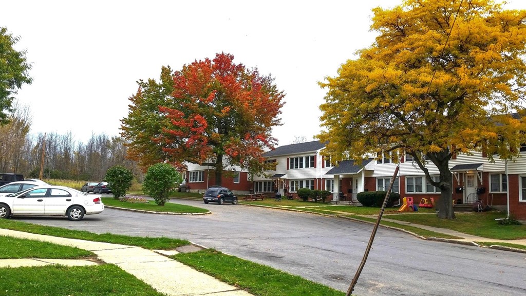 a street in a neighborhood with cars parked in front of houses