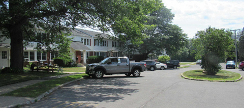 a street with cars parked in front of a house