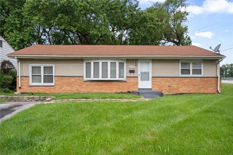a small brick house with a lawn in front of it