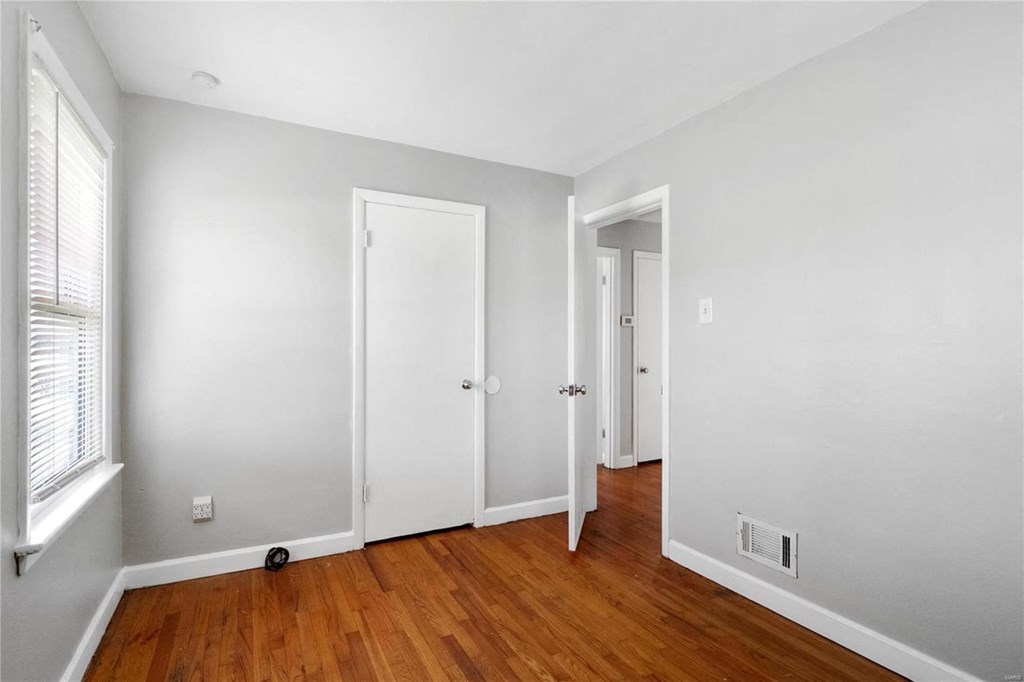 a bedroom with a hard wood floor and white walls