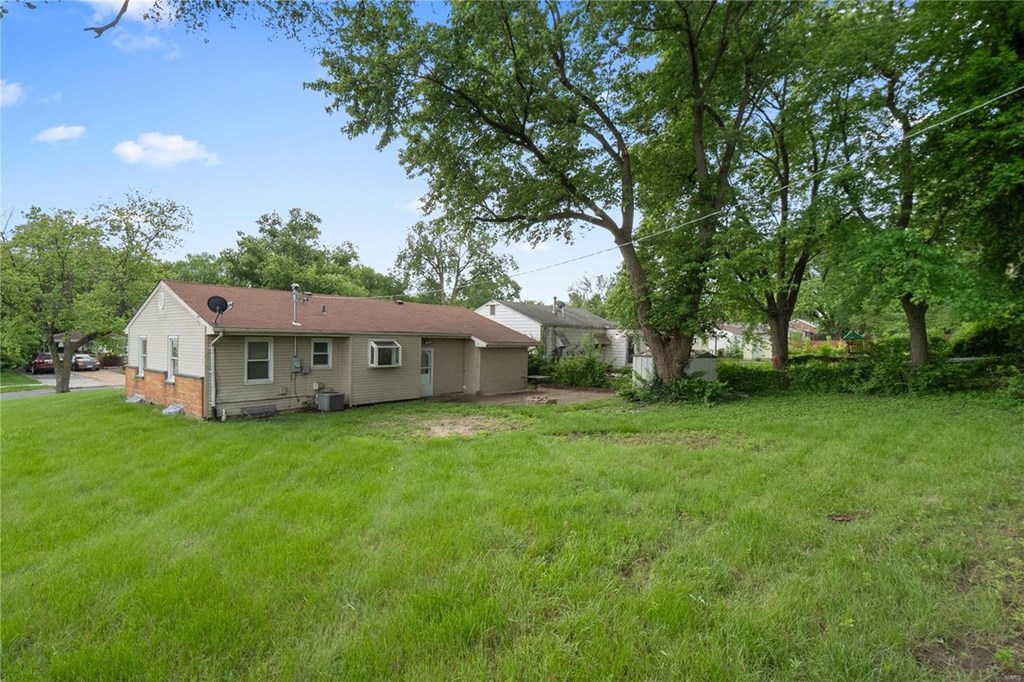 a view of the back of a house with a yard and trees