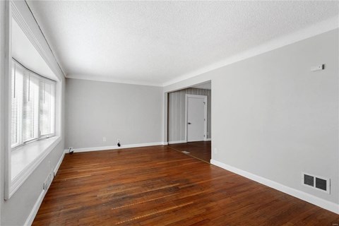 the spacious living room with wood flooring and a large window