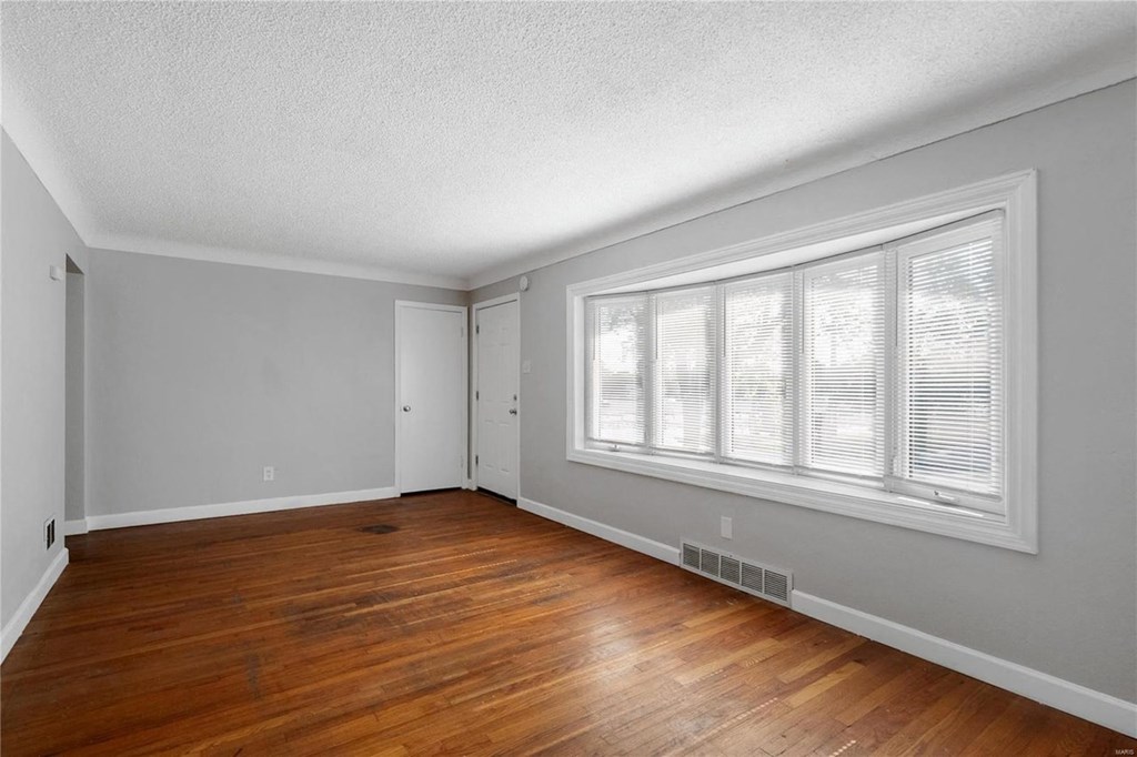 an empty living room with wood floors and a large window