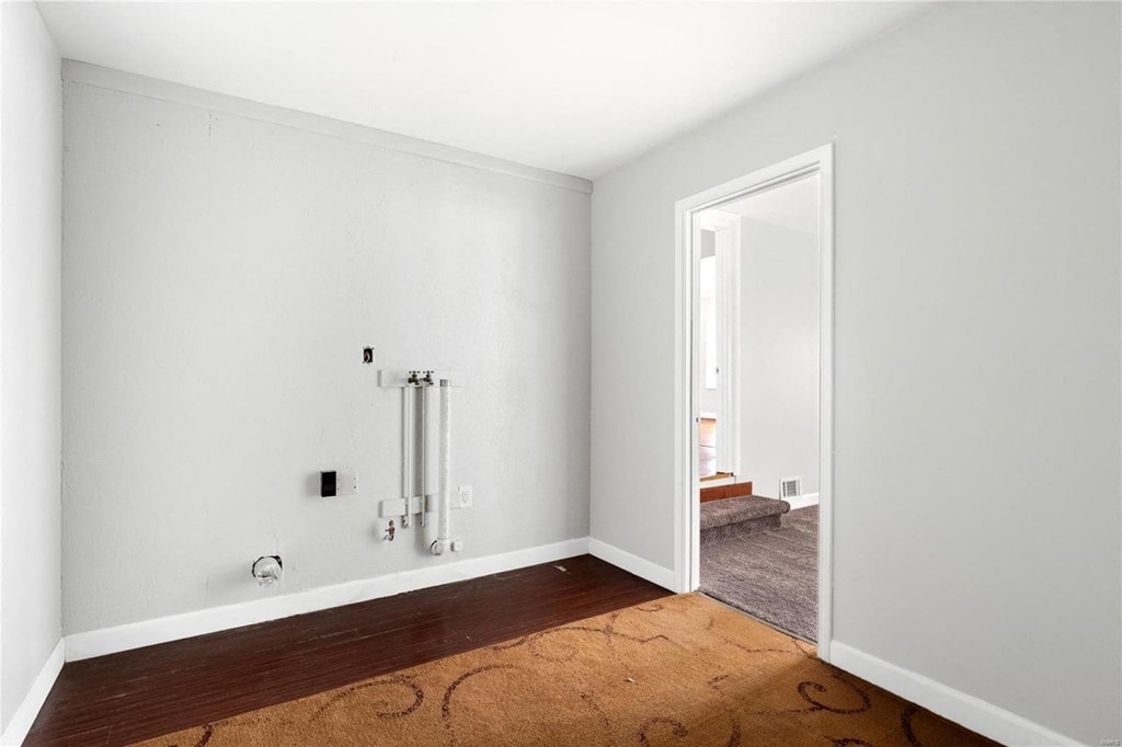a room with white walls and a hard wood floor and a shower