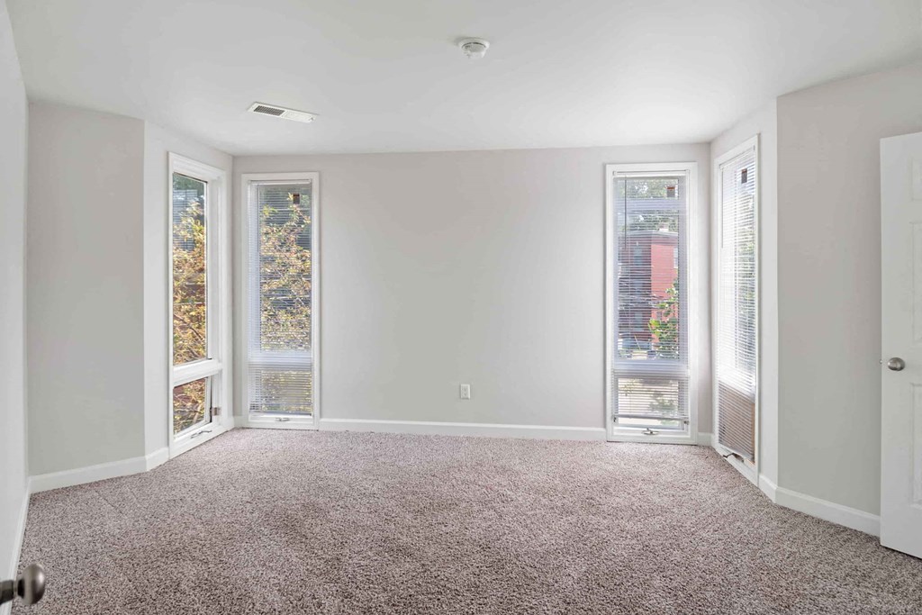 A room with a carpeted floor and a ceiling fan.