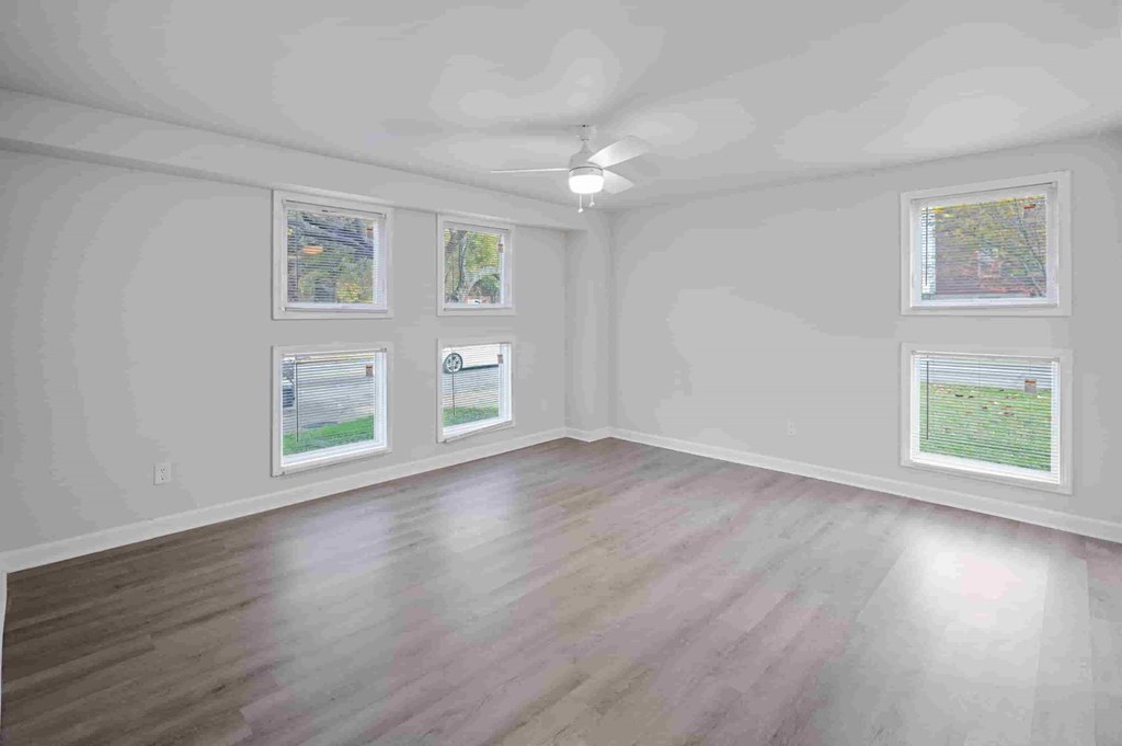 A room with a ceiling fan and four paintings on the wall.