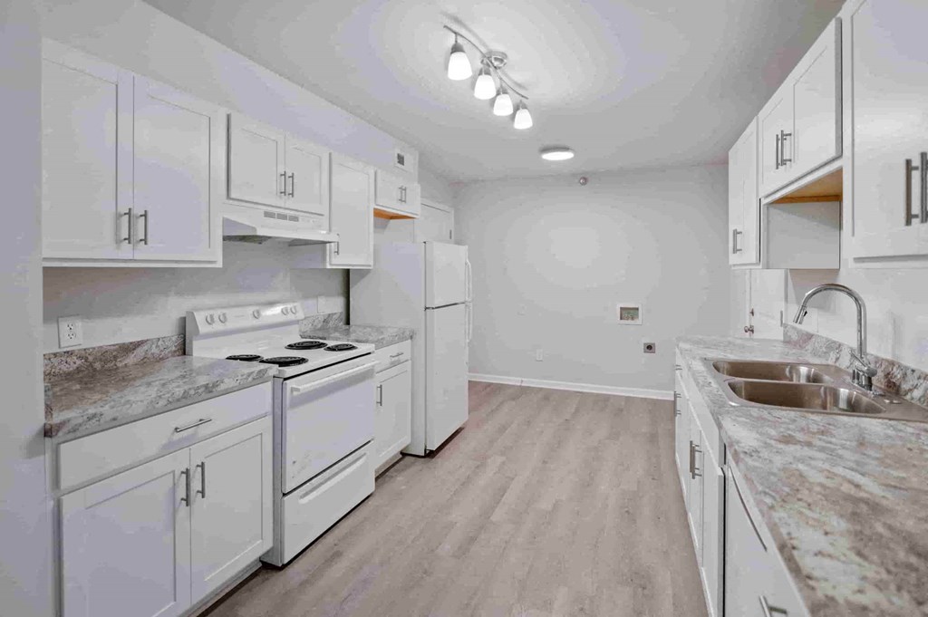 A kitchen with white cabinets and a marble countertop.