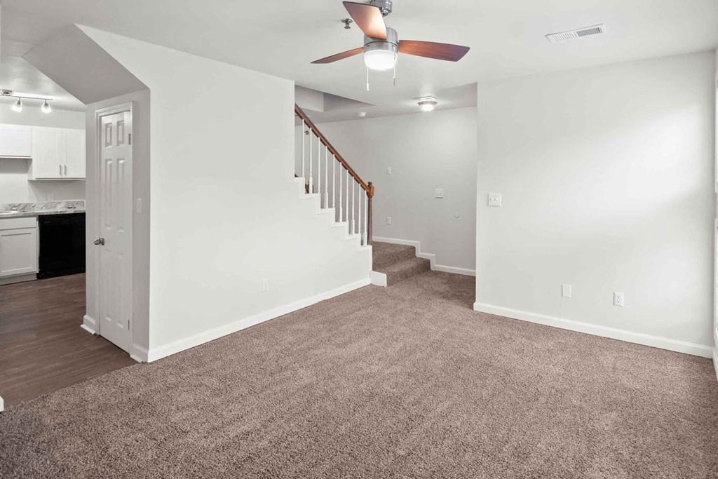 A room with a staircase and a ceiling fan.