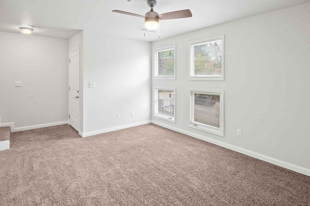 A room with a carpet floor and a ceiling fan.