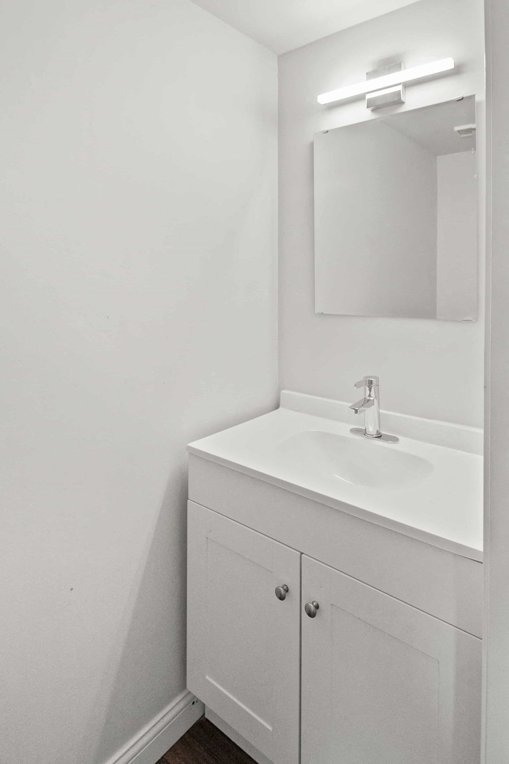 A white bathroom vanity with a sink and mirror.