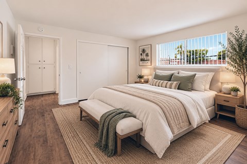 A bedroom with a large bed and a window with blinds.
