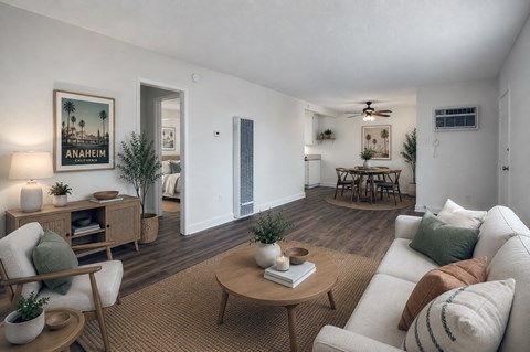 A living room with a white couch, a wooden coffee table, and a painting of Anaheim.
