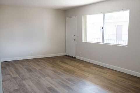 A room with a wooden floor and a window with a view of a building outside.