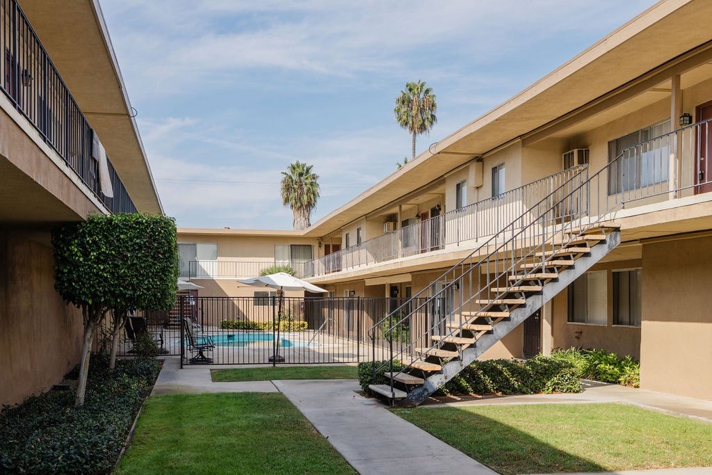 A building with a pool and a palm tree in the background.