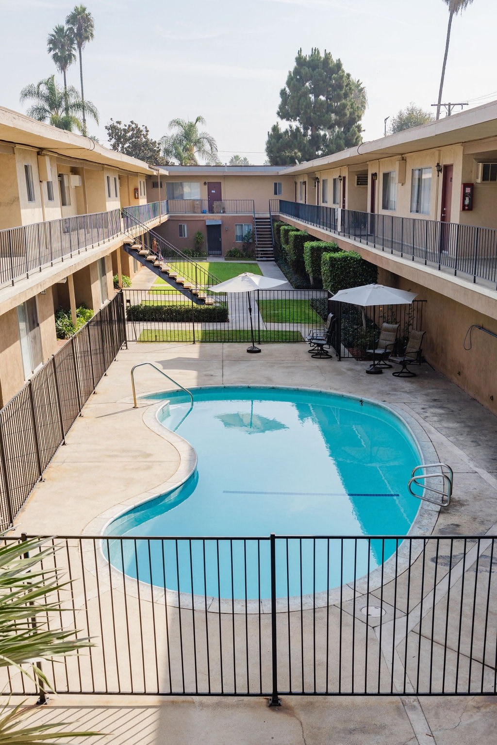 A black fence surrounds a small pool in a courtyard.