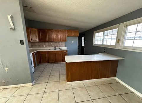 a kitchen with a white counter top and wooden cabinets