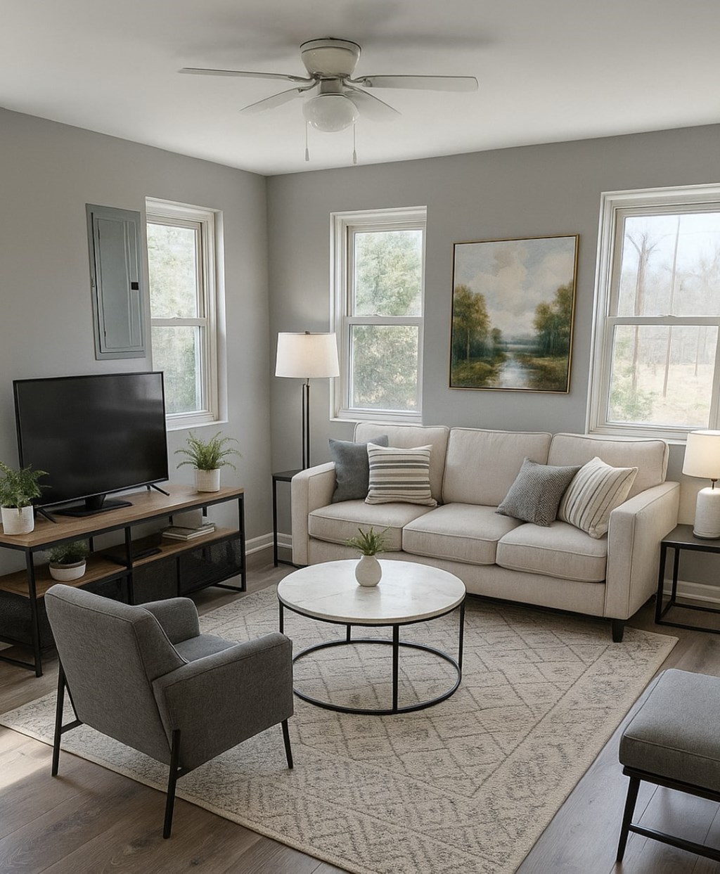A living room with a grey chair, a white couch, a television, and a painting on the wall.