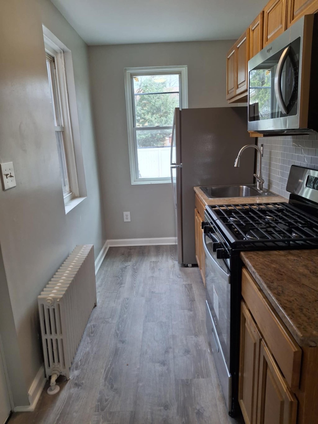 A kitchen with a black stove top oven and wooden cabinets.