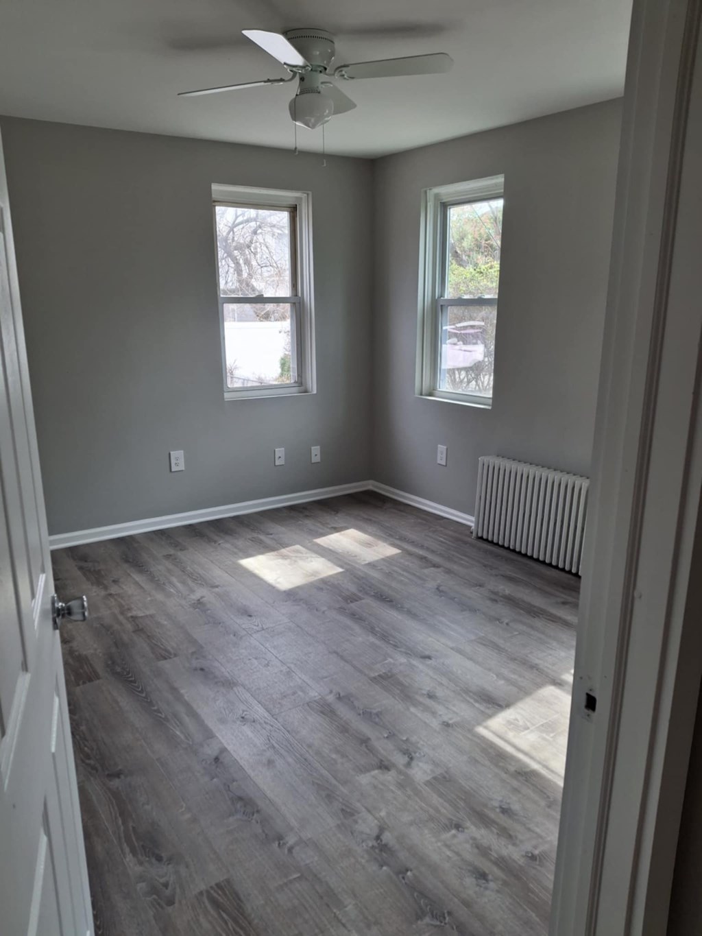 A room with a ceiling fan and two windows.