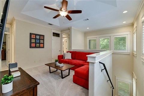 a living room with a red couch and a ceiling fan