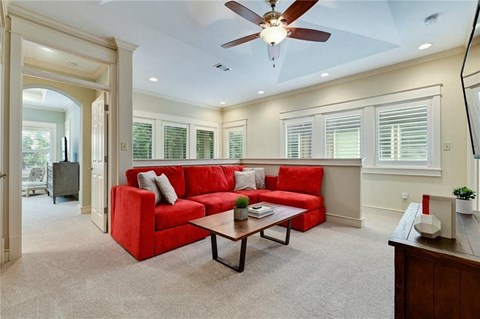 a living room with a red couch and a ceiling fan