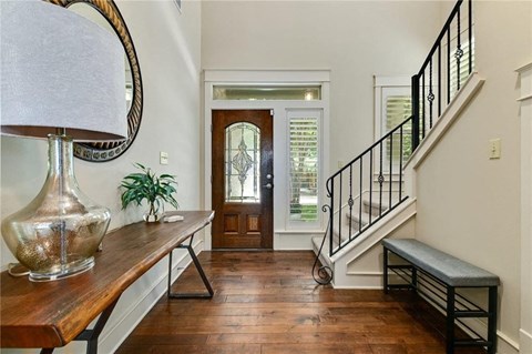 the entryway of a house with a staircase and a wooden door