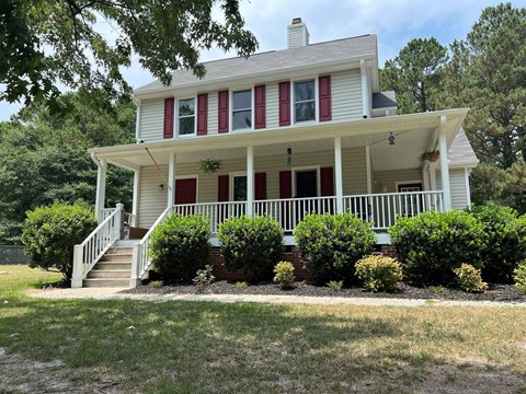 A white house with red shutters and a porch.