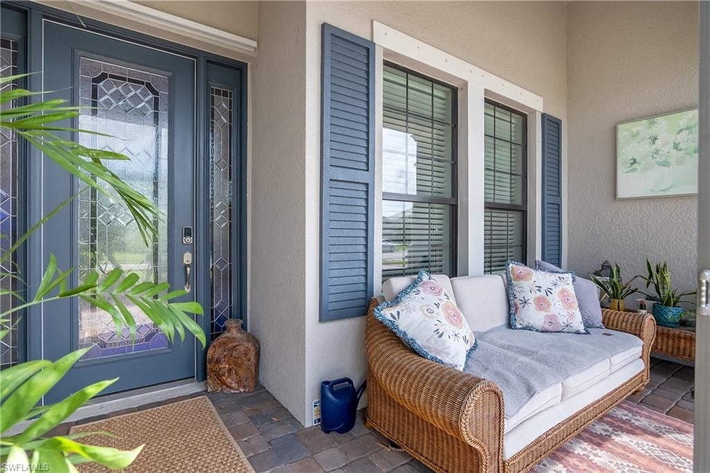 a front porch with a wicker couch and blue doors