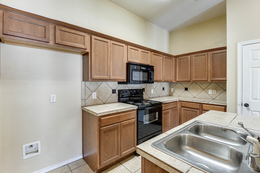 an empty kitchen with wooden cabinets and black appliances