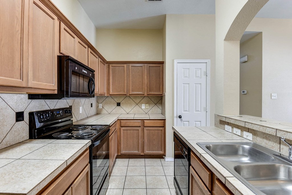 a kitchen with wooden cabinets and a black stove and a sink