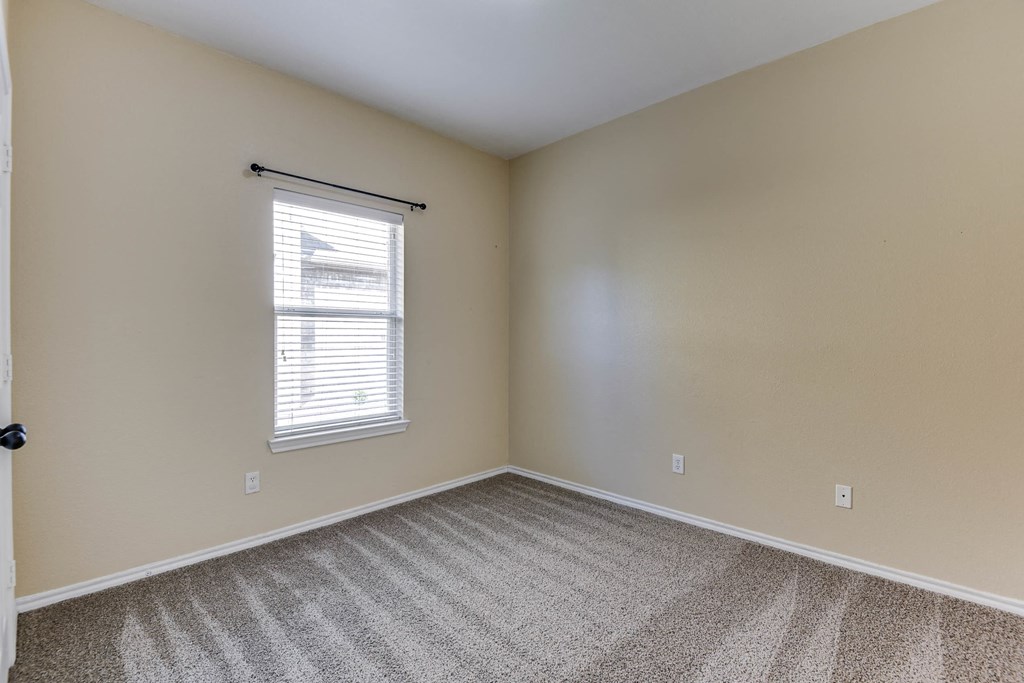 an empty bedroom with carpet and a window
