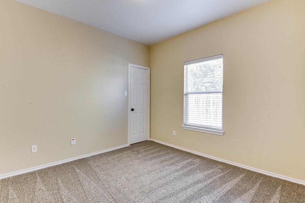 an empty bedroom with a window and a door
