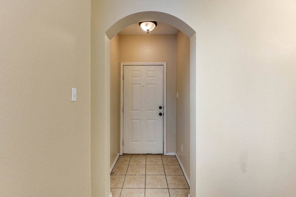 an empty hallway with a white door and a tiled floor