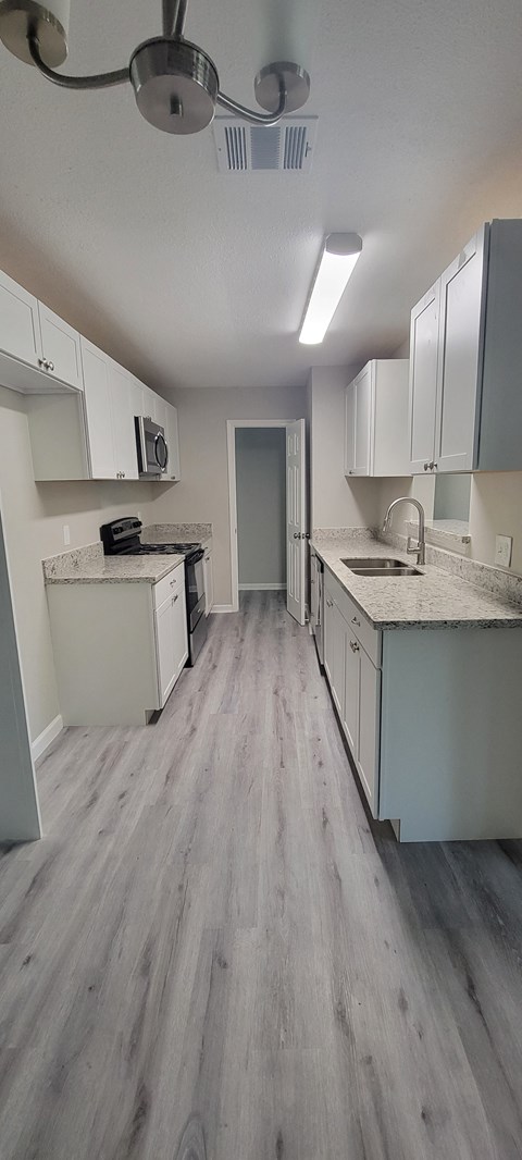 an empty kitchen with white cabinets and stainless steel appliances