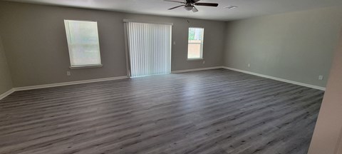 an empty living room with wooden floors and a ceiling fan
