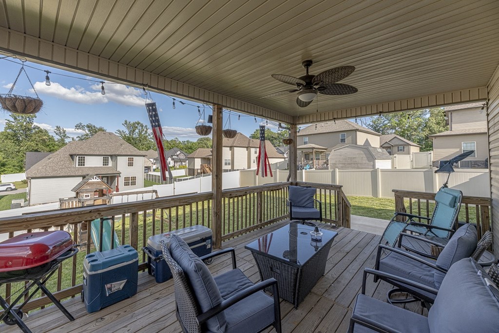 a covered deck with furniture and a ceiling fan
