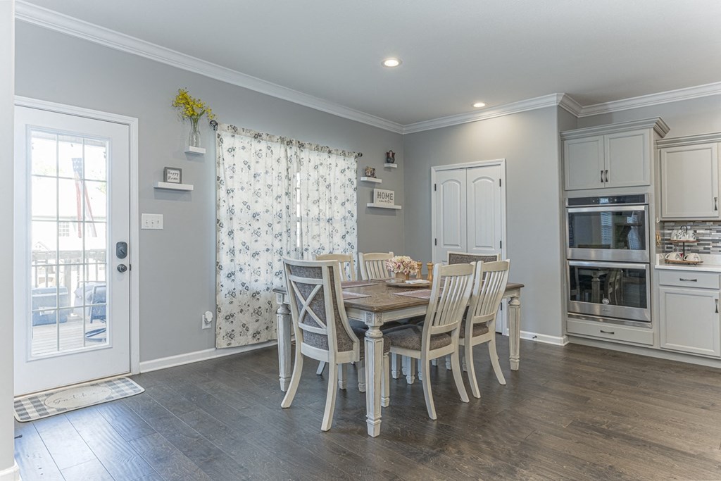 a dining room with a table and chairs and a kitchen with an oven