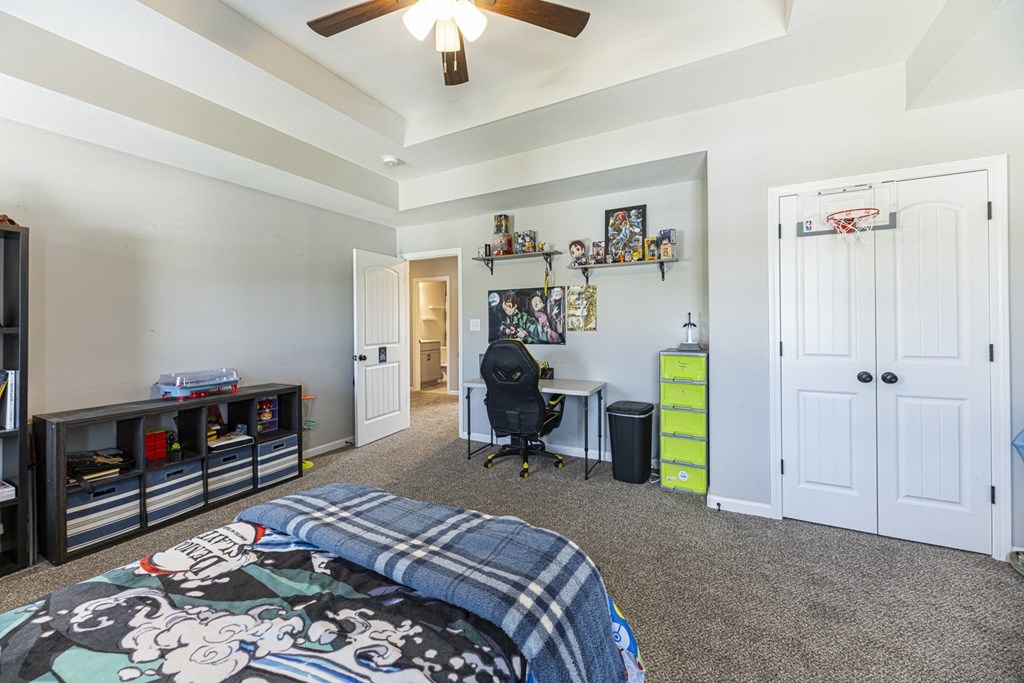 a bedroom with a bed and a desk and a ceiling fan