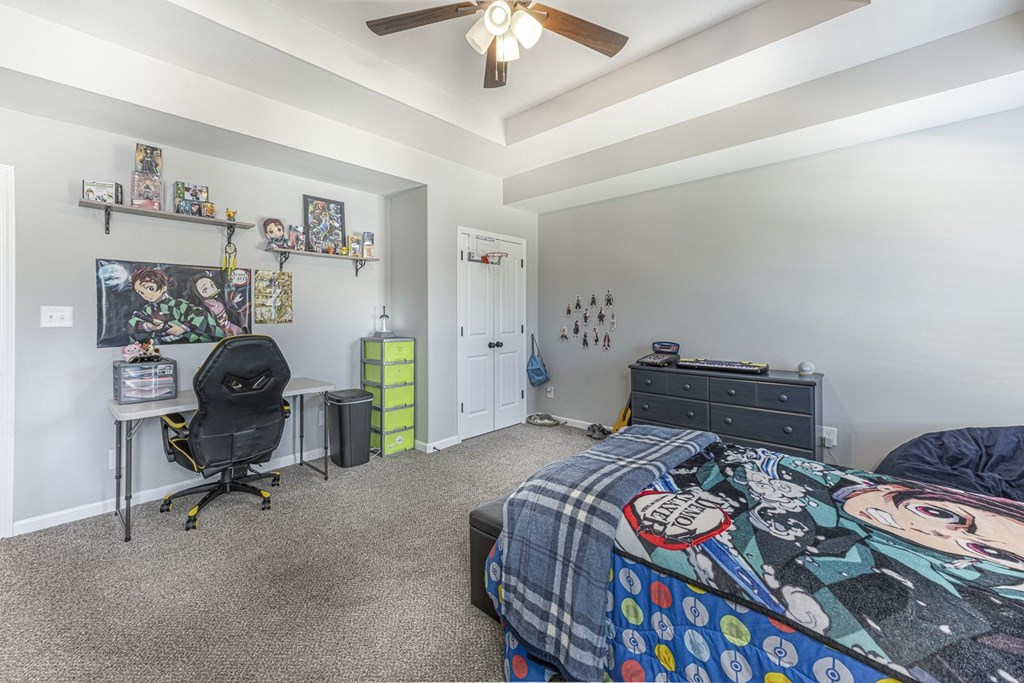 a bedroom with a bed and a desk and a ceiling fan