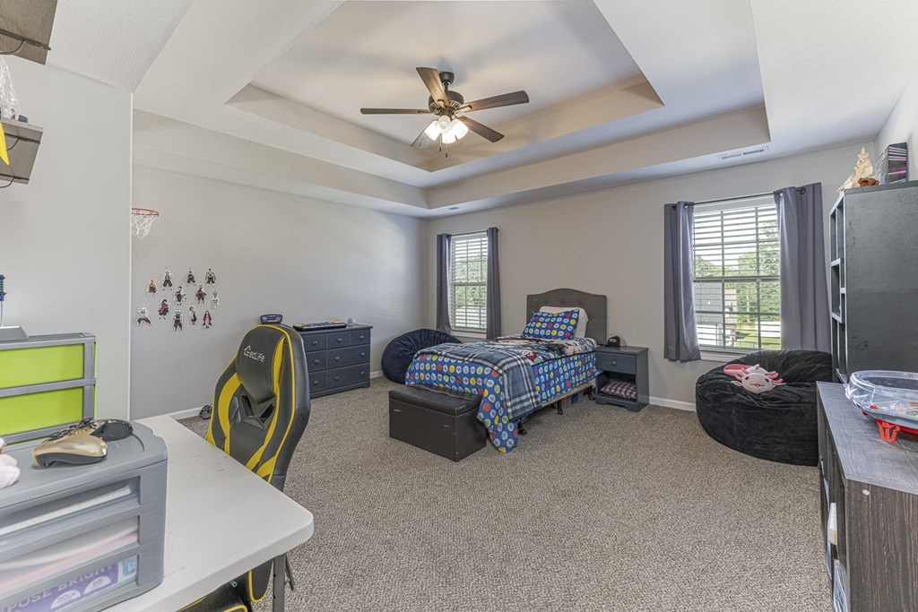 a bedroom with a bed and a desk and a ceiling fan