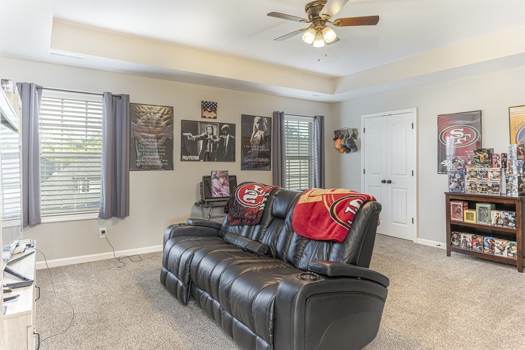 a living room with a leather couch and a ceiling fan