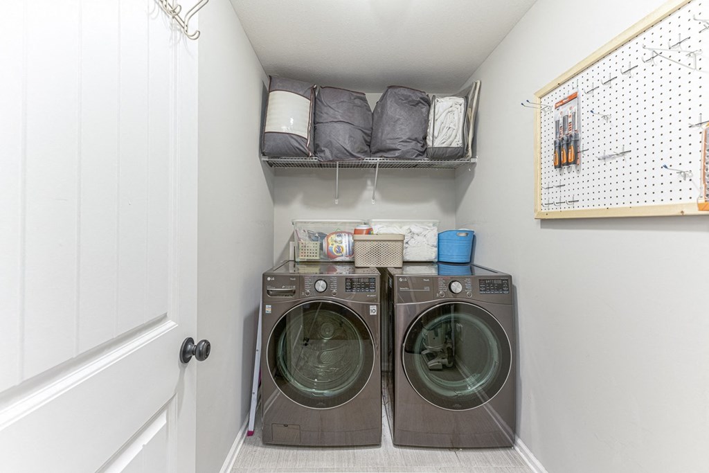 a small laundry room with a washer and dryer and a shelf above it