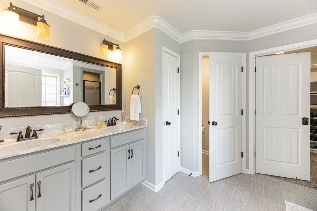 a bathroom with white cabinets and a sink and a mirror