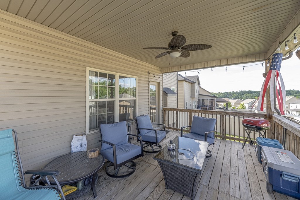 a covered deck with blue chairs and a ceiling fan