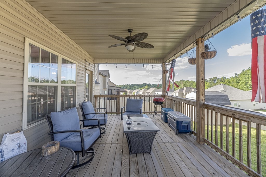 a covered deck with a ceiling fan and chairs and a table