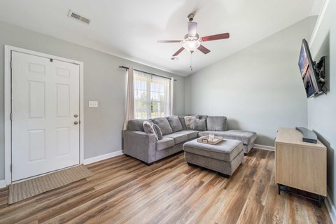 A living room with a grey couch and a wooden floor.
