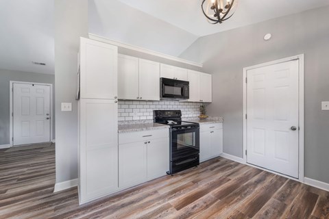 A kitchen with white cabinets and a black oven.