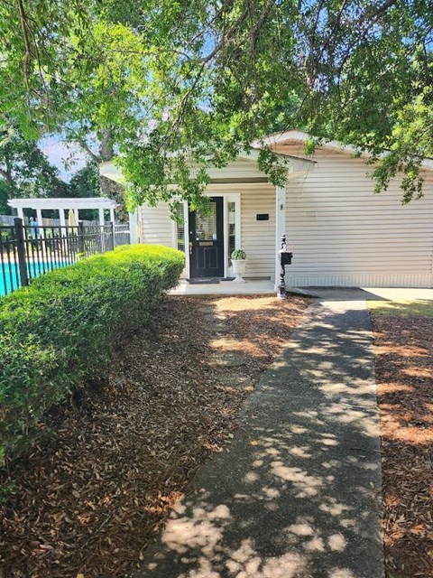 a sidewalk in front of a white house and a pool
