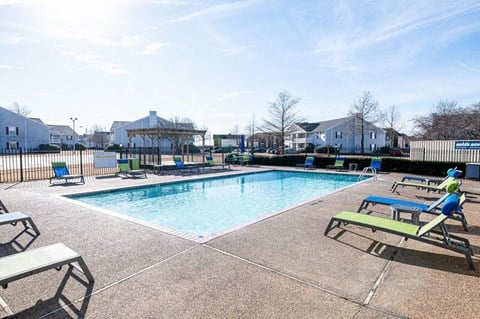 A sunny day at the pool with lounge chairs and a picnic table.